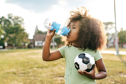 Child in a park taking a break from playing soccer near Detailed Dental Care.