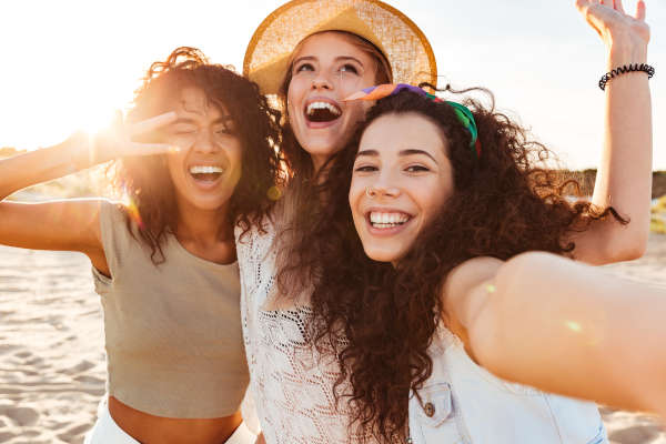 Image of young women smiling on a beach near Detailed Dental Care.